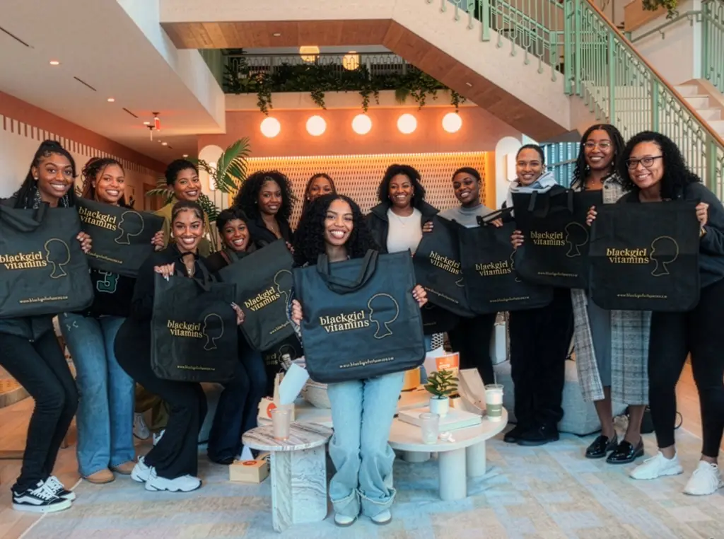 Group of women holding Black Girl Ventures tote bags at a community event