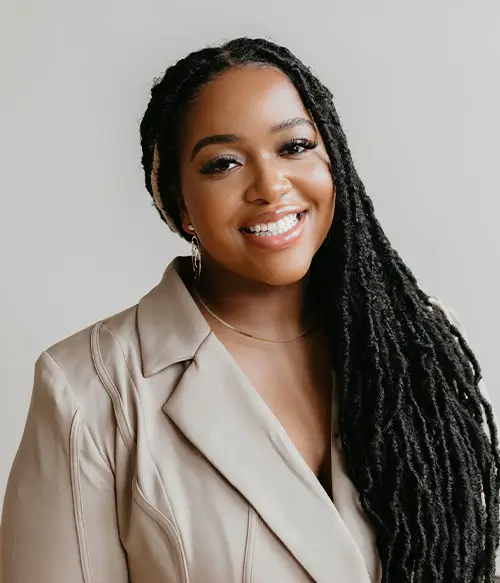 Smiling woman with long braided hair in beige blazer